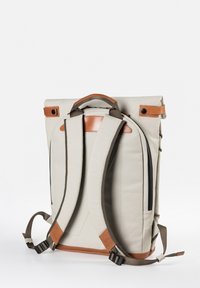 Beiger Rucksack mit gepolsterten Schulterriemen, Lederakzenten, Tragegriff oben und seitlichen Druckknopfverschlüssen, aufrecht stehend vor weißem Hintergrund.