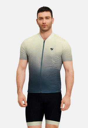 Mann trägt ein kurzärmeliges, reißverschlussbedecktes Radtrikot mit Gelb-zu-Grau-Verlauf und schwarze Radhosen vor einem einfarbigen Hintergrund.