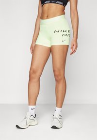 Pantalones cortos Nike Pro de color verde neón con cintura elástica y letras negras en negrita. Tela suave, diseño ajustado y pequeño detalle de logo contrastante.
