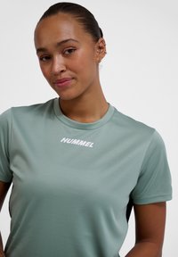 Mint green athletic t-shirt made of smooth fabric, featuring a round neckline, short sleeves, and a white "HUMMEL" logo at the center.