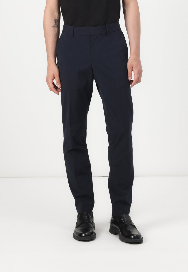 Pantalones azul marino hechos de una tela suave, con un corte ajustado, una silueta elegante y una cintura estándar con trabillas para el cinturón.