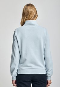 Light blue sweatshirt with a high collar, ribbed cuffs and hem, made from a soft textile. Smooth texture with no visible patterns.
