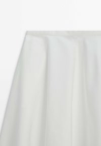 Jupe gris clair, longueur au genou, avec une texture lisse et satinée, présentant des plis simples et une ceinture large et plate.