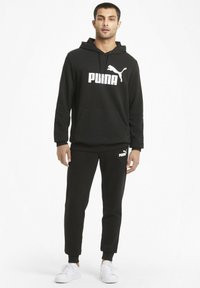 Conjunto de sudadera con capucha y pantalones de chándal, hecho de material de forro polar. Presenta el logo de Puma en blanco en el pecho y en los pantalones, con puños acanalados y bolsillos.