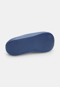 Suola in gomma blu con grip testurizzato, caratterizzata da piccoli punti rialzati e un design aerodinamico. Accenti del logo sottili vicino al tallone.