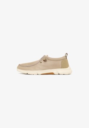 Beige casual instapschoen met witte zool, elastische veterstop, gevoerde hielkraag en trek lus aan de achterkant.