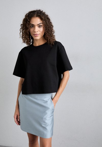 Μαύρο κοντό μπλουζάκι με κοντά μανίκια, συνδυασμένο με ελαφριά μπλε μίνι φούστα που διαθέτει λεία υφή και πλαϊνές τσέπες.