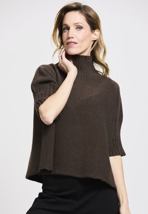 Brauner, kurzärmeliger Strickpullover mit hohem, geripptem Kragen und lockerer Passform. Die Textur wirkt weich und hat am Saum einen leichten Fall.
