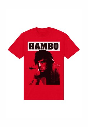 Rød bomulds t-shirt med et grafisk motiv af en muskuløs figur og en helikopter, med "RAMBO" trykt ovenfor i fede sorte bogstaver.