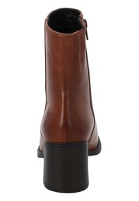 Botín de cuero marrón hasta el tobillo con punta redonda, cremallera lateral y un tacón negro moderado, que presenta un detalle de logotipo en relieve en el lado.