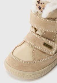 Beige semsket og nylon ankelstøvel med to borrelås, pelskledning og strukturert gummisåle; har en GORE-TEX-logo detalj.