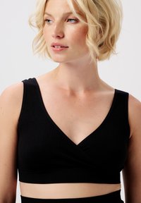 Schwarzes, geripptes Bralette mit V-Ausschnitt, breiten Trägern und einem Unterbrustabband. Der Stoff ist weich und dehnbar, ideal für Freizeitkleidung.