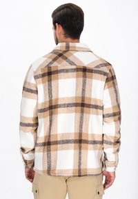 Herrskjorta i rutigt fleece i beige, brunt och vitt. Har krage med knappar och långa ärmar i en avslappnad passform och mjuk textur.