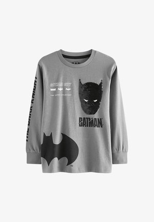 Szürke hosszúujjú póló Batman grafikával, beleértve egy flitteres Batman maszkot, egy nagy fekete denevérlogót és a szövegeket: "Gotham City," "A Köpenyes Keresztapa."