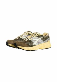 Sneaker con un design in materiali misti, che presentano camoscio marrone, pannelli in rete e una suola in gomma gialla chiara. Accentuati da dettagli grigi e bianchi.