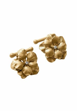 Gemelos florales de tono dorado con pétalos texturizados y una pequeña gema clara en el centro, sobre un fondo blanco.