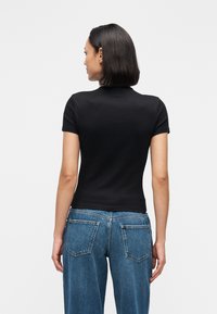 Camiseta negra de manga corta con diseño ajustado, textura de algodón suave y cuello redondo, combinada con jeans de mezclilla azul de tiro alto con bolsillos.