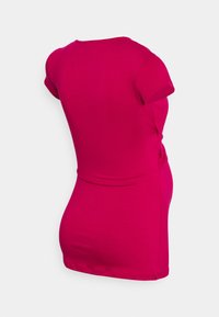 Top ajustado en rosa brillante, hecho de algodón suave, con mangas cortas y un detalle fruncido en el costado.