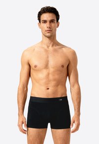 Black men's boxers made of smooth fabric, featuring a wide elastic waistband and a fitted design for support. No visible patterns or logos.
