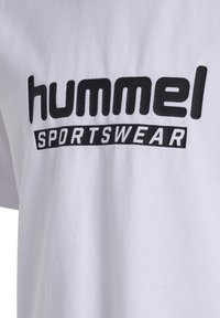 Vit bomull t-shirt med en iögonfallande svart "hummel" logotyp och texten "SPORTSWEAR", med en mjuk textur och korta ärmar.