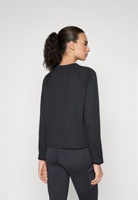 Black ribbed long-sleeve top with a round neckline and raglan sleeves, featuring a cropped fit and textured fabric.