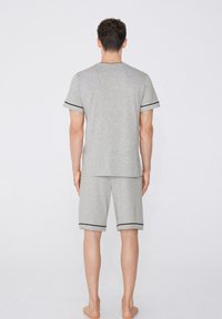 Conjunto de pijama corto de algodón gris con ribetes negros en las mangas y en los pantalones cortos, que presenta un ajuste relajado y un diseño recto.