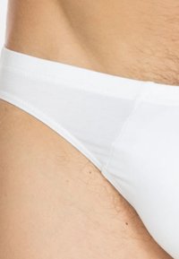 Weiße Baumwollslips mit glatter Textur, schmalem Bund und enganliegendem Design, das einen Teil der Hüfte und die umliegende Haut zeigt.