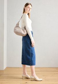 Beżowa torba hobo, kremowa bluzka z długim rękawem, dżinsowa spódnica midi oraz beżowe buty na obcasie z paskami na kostkach. Gładkie tekstury i nowoczesny design.