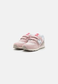 Baskets roses et grises avec un dessus en daim et en mesh, des bandes Velcro, une semelle extérieure blanche, et un logo "N" bien visible sur les côtés.