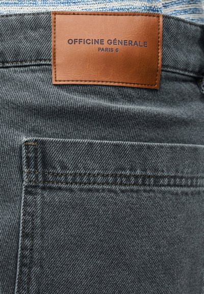 Υφασμα από σκούρο γκρι τζιν με υφή στην επιφάνεια. Διαθέτει καφέ δερμάτινη ετικέτα με την επιγραφή «OFFICINE GÉNERALE» σε μπλε χρώμα. Ορατή οριζόντια τσέπη.