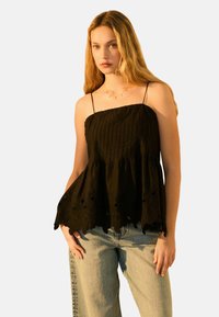 Haut sans manches noir en tissu texturé, corsage froncé et dentelle à l'ourlet avec des découpes florales. Assorti à un pantalon en denim clair.