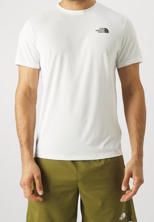 Homme portant un T-shirt blanc à manches courtes North Face et un short vert olive North Face, debout avec les bras détendus le long du corps.