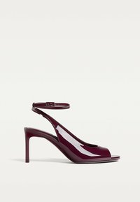 Burgundy patento nahka slingback korkokengät, joissa on avointoedessä oleva muotoilu, säädettävä nilkkahihna ja hoikka stiletto-korko. Sujuva pinta ja kiiltävä viimeistely.