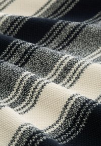 Geverfd doek met afwisselende dikke strepen in donker marineblauw en crème, met een textuur oppervlak en fijne details in het weefpatroon.