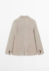 Blazer beige texturé lin avec manches longues, col cranté, fente centrale au dos et détails de boutons noirs sur les poignets, vu de dos.