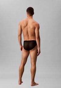 Zwarte, gestreepte herenonderbroeken met een textuurdesign, voorzien van een effen tailleband en een snug fit. Gezien vanaf de achterkant.