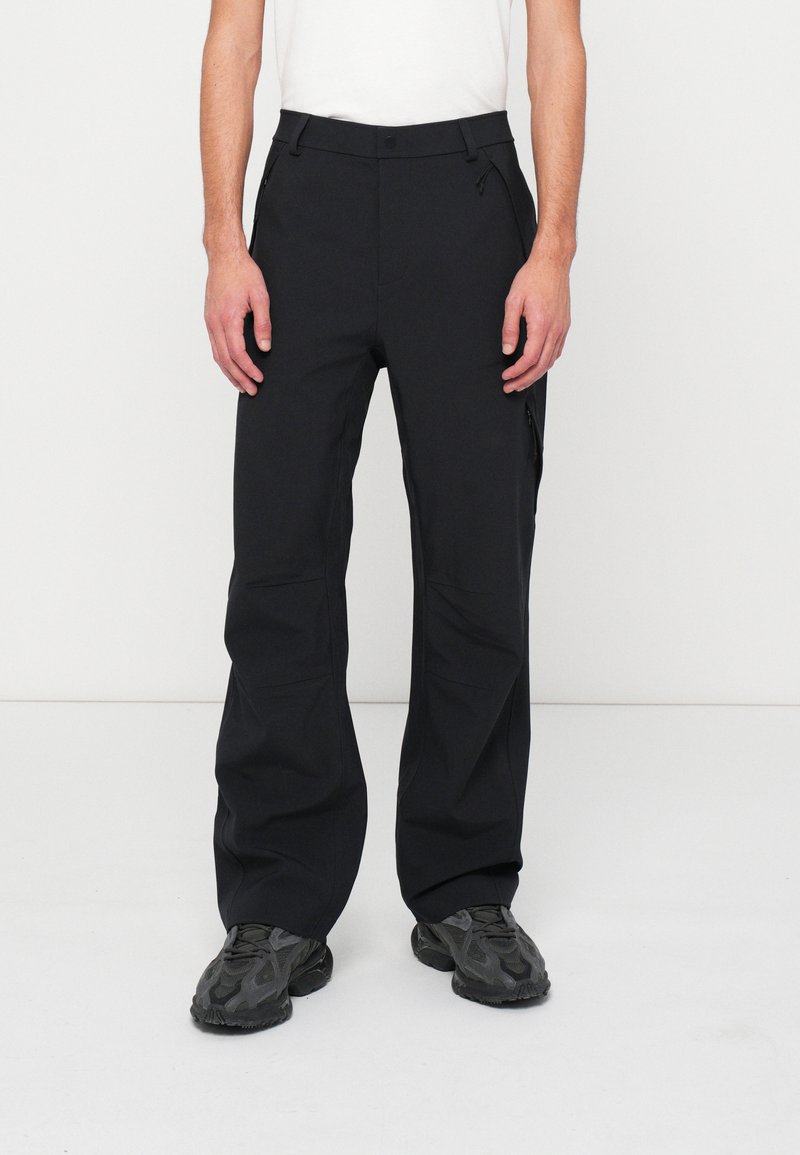 Fekete technikai nadrág egyenes szabással, oldalsó cipzáras zsebekkel és övbújtatókkal. Sima, tartós anyag, letisztult dizájnnal.