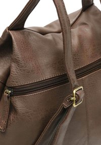 Rudas odinis krepšys su tekstūruota paviršiumi, turintis viršutinį užtrauktuką ir šoninį kišenę. Rankena pritvirtinta žalvario sagtimi.