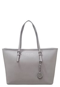 Sac tote synthétique gris avec deux poignées, texture lisse, accents en métal, et un charme logo suspendu. Marque Michael Kors sur le devant.
