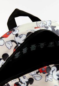 Sac à dos avec une surface lisse et brillante, arborant un motif de dessin animé de Mickey Mouse en noir, rouge et blanc. Fermeture éclair noire et étiquette intérieure.