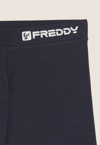 Leggings elasticizzati blu navy con una texture morbida, dotati di una fascia larga in vita con la scritta "FREDDY" in lettere bianche. Design semplice e minimale.