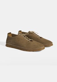 Chaussures en tissu perforé marron avec un bout arrondi, un laçage sur le devant et une semelle en caoutchouc dotée de petites rainures pour une meilleure traction.