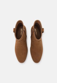 Braune Wildleder-Ankle Boots mit runder Spitze, leichtem Absatz, seitlichem Reißverschluss und einer weichen Textur mit minimalen Nähten.