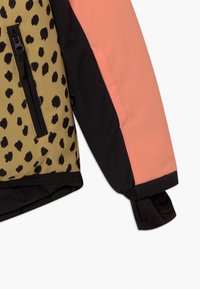 Farbige Jacke mit Leopardenmuster in Beige und Schwarz, mit korallfarbenen und schwarzen Ärmeln; beinhaltet eine Reißverschlusstasche und elastische bündchen.