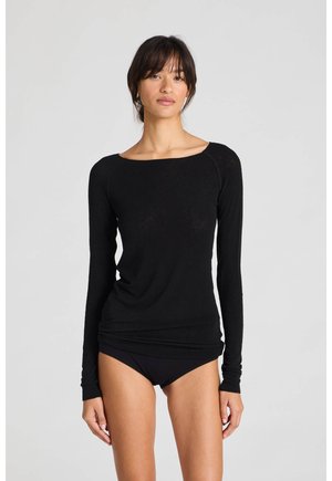 Top nero a maniche lunghe con scollatura ampia, texture morbida e design aderente. Indossato con pantaloni neri, esposto su uno sfondo neutro.