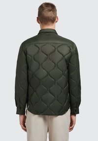 Groene gewatteerde shirtjacket met een ruitquiltpatroon, knoopmanchetten en een kraag. Soepele, satijnachtige textuur.