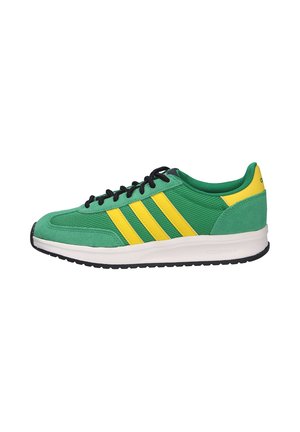 Sneaker verde e giallo con lacci neri, suola bianca e tre righe gialle sul lato, visto dal lato esterno.