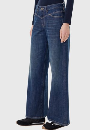 Jeans in denim a gamba larga di colore blu scuro, con chiusura con bottoni e cerniera, tasche anteriori e finitura texturizzata. Rifiniti con dettagli in metallo dorato.