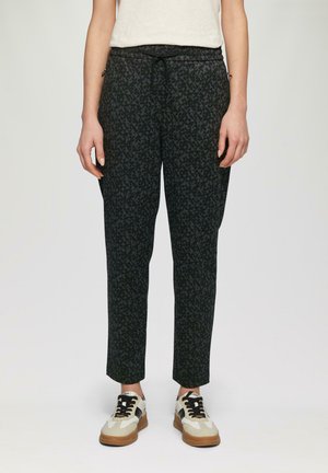 Pantalons noirs avec un motif géométrique, taille élastique et cordon de serrage. Associés à des baskets décontractées beiges et noires.