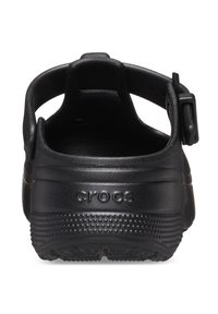 Zwarte rubberen Crocs met een achterkantband, met een gestructureerd oppervlak en kleine verhogingen op de zool, gelabeld "crocs" aan de zijkant.